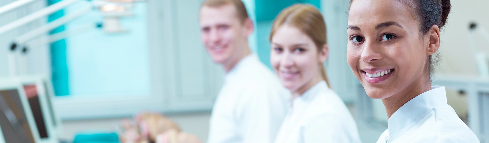three diverse dental students sitting at table smiling.