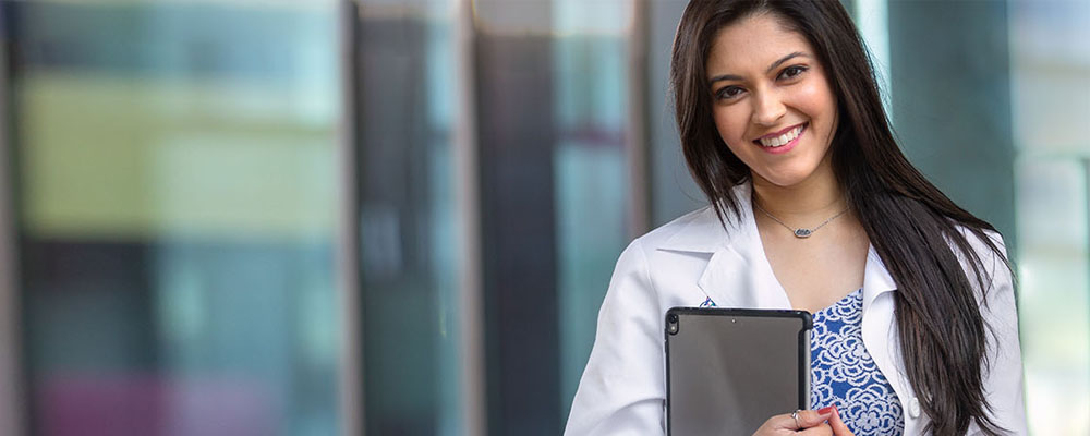 Woman smiling and holding a laptop.