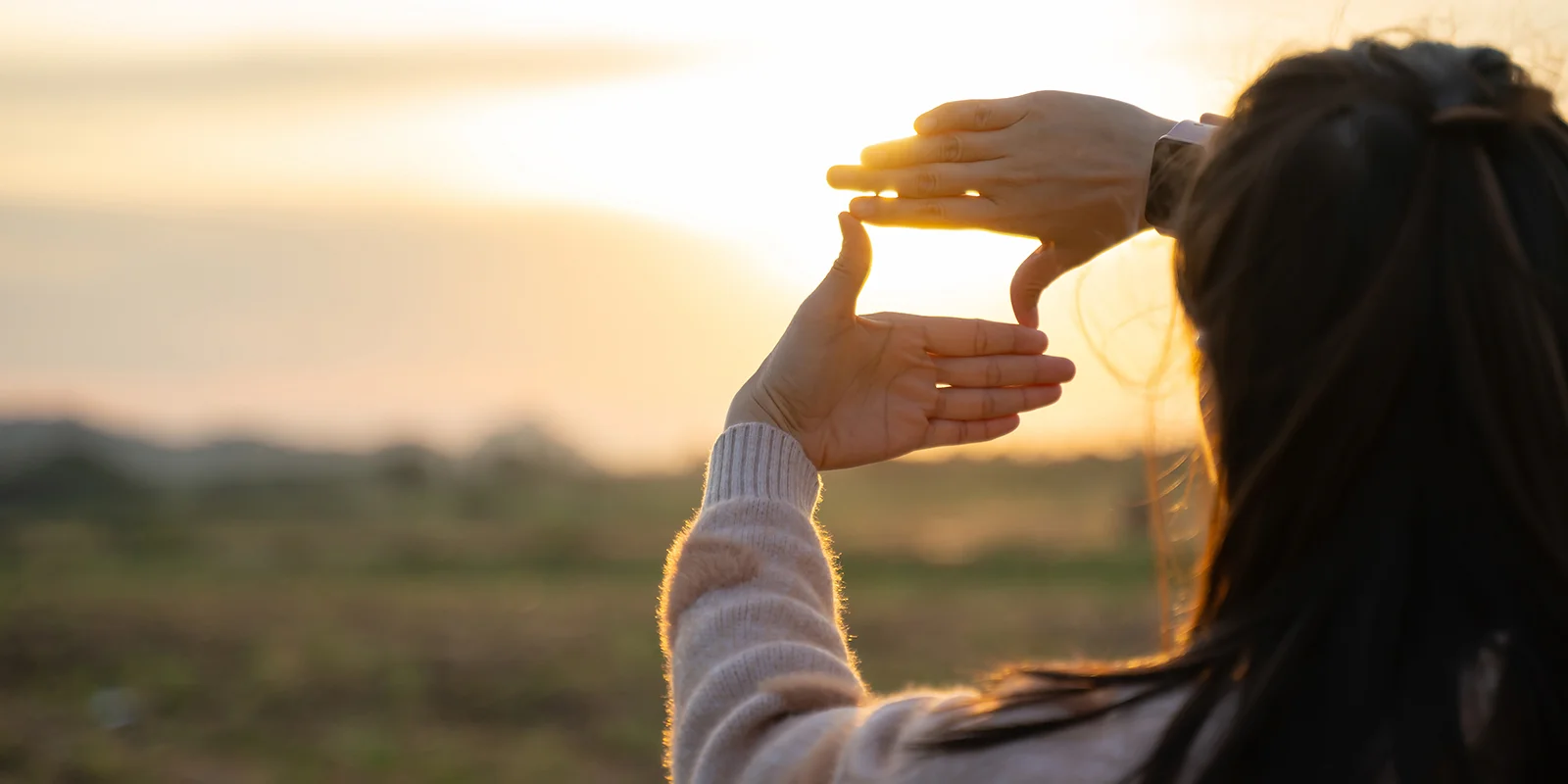 woman making a box shape with her fingers and looking towards horizon