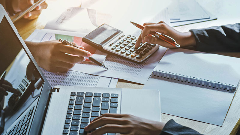Two people pointing at financial papers and using a calculator