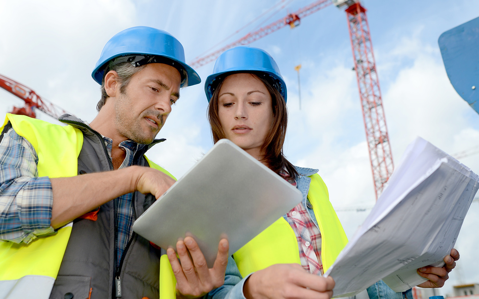 Two construction workers in blue helmet discussing project