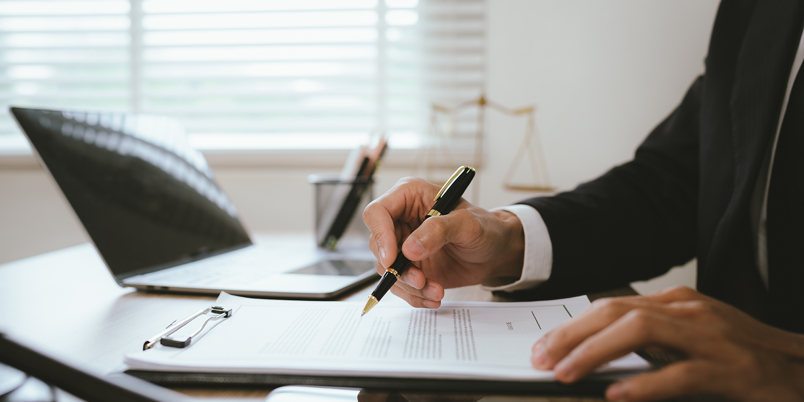 Close-up of a lawyer reviewing and signing a legal contract at an office desk