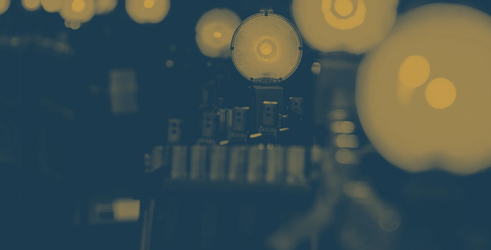 Row of illuminated light bulbs with a central bulb in sharp focus against a dark background, highlighting filament details and industrial setup.