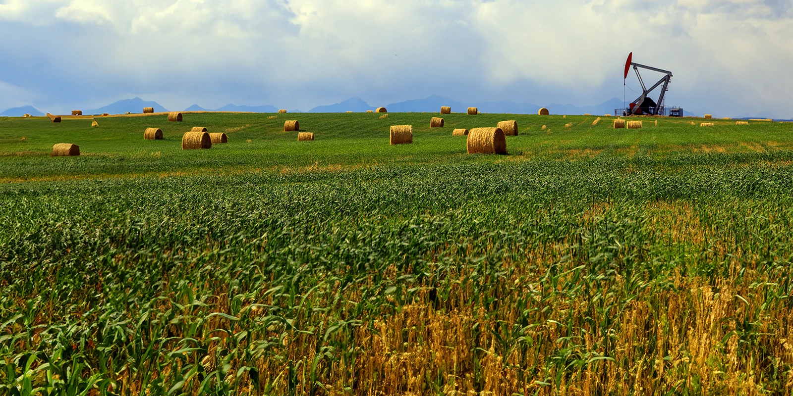 Alberta prairies with a pumpjack and mountains in the background