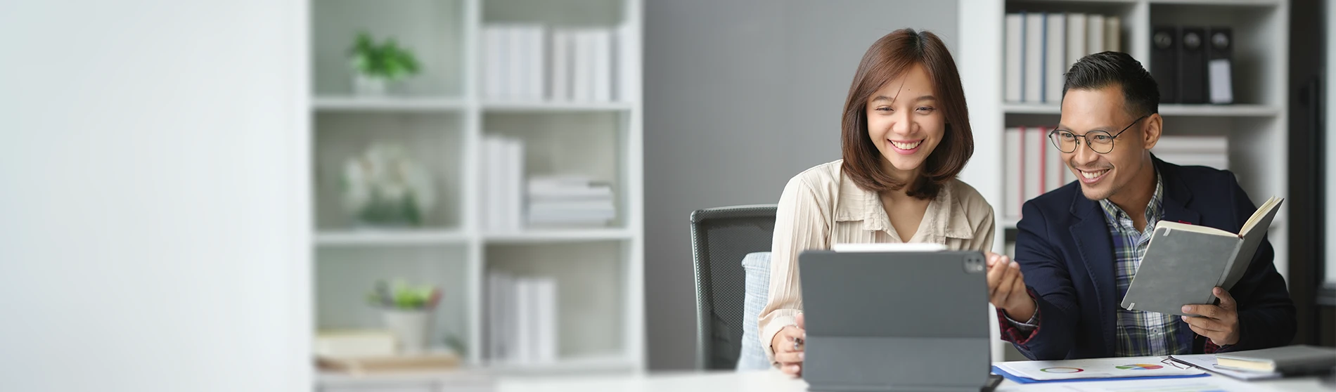Deux personnes analysant des données sur une tablette numérique et discutant de comptabilité