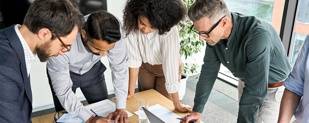 Group of workers looking at a document on a desk.