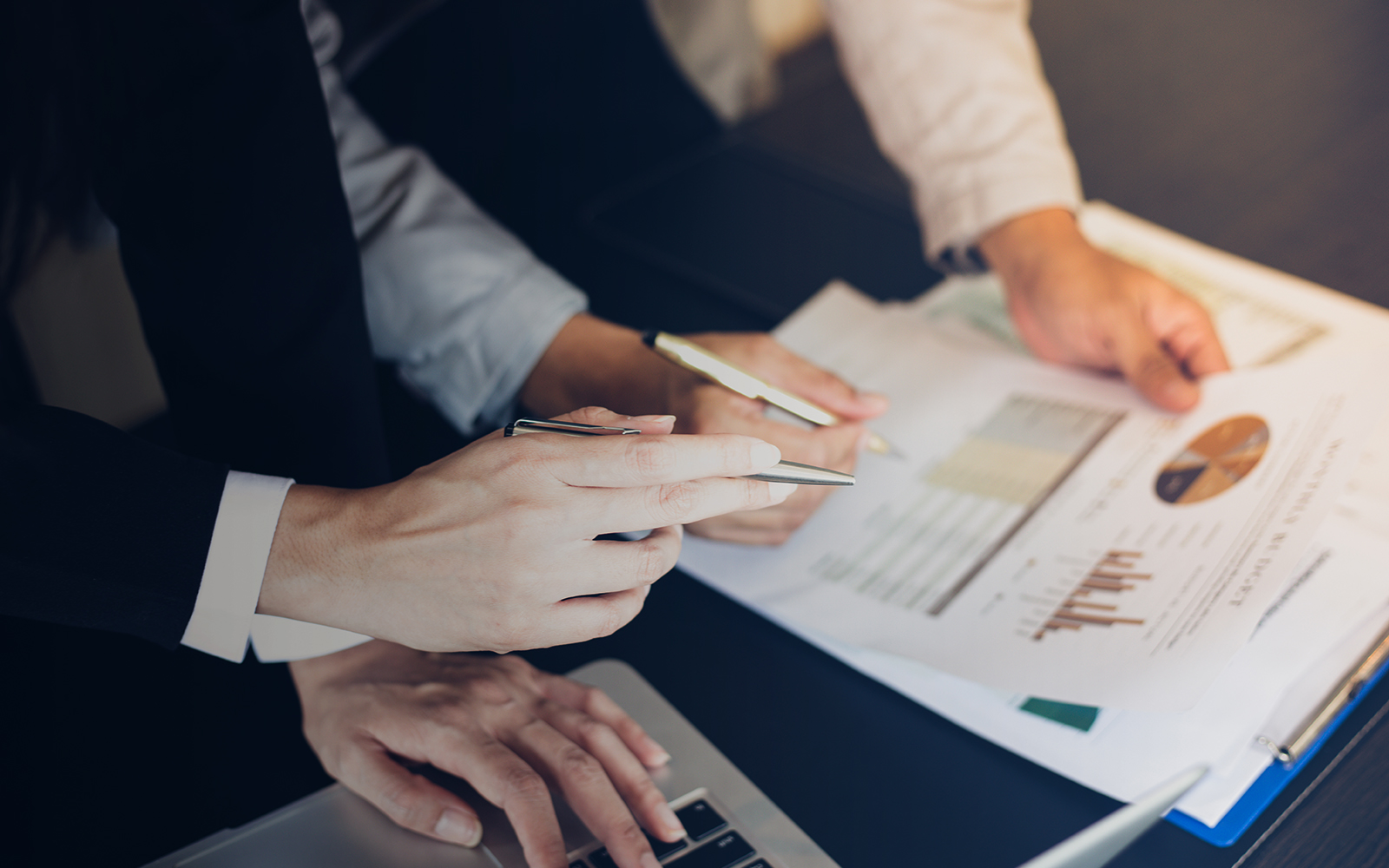 two persons discussing business report projections on desk