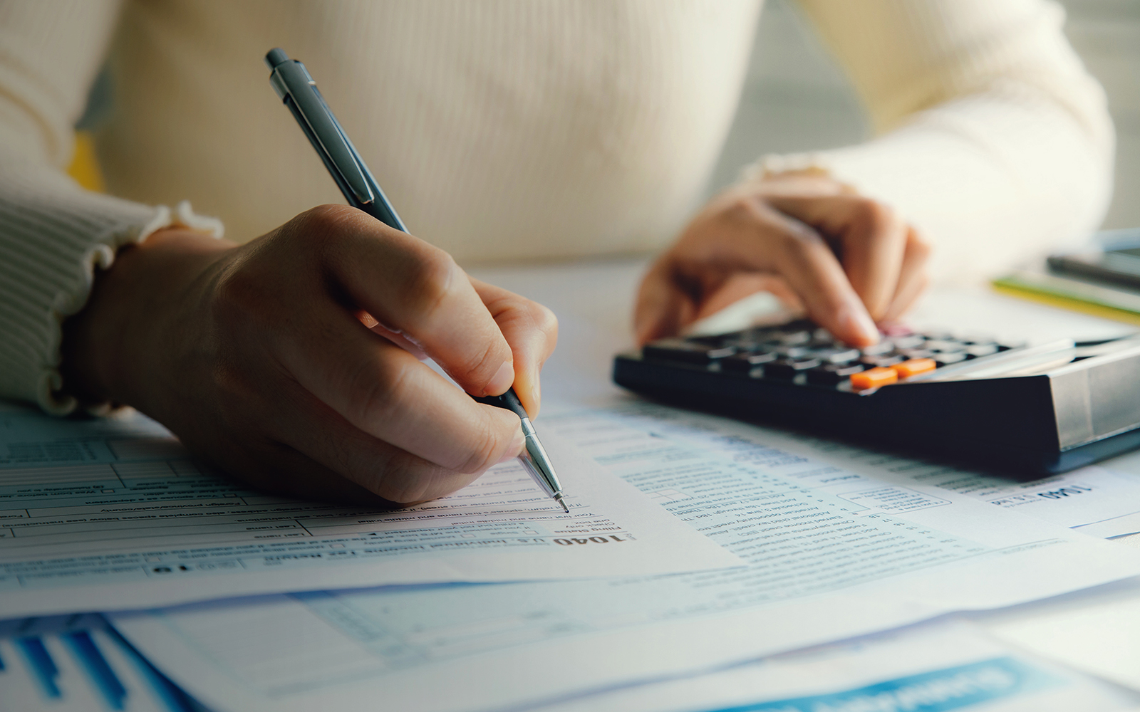 persons doing finances using calculator on desk