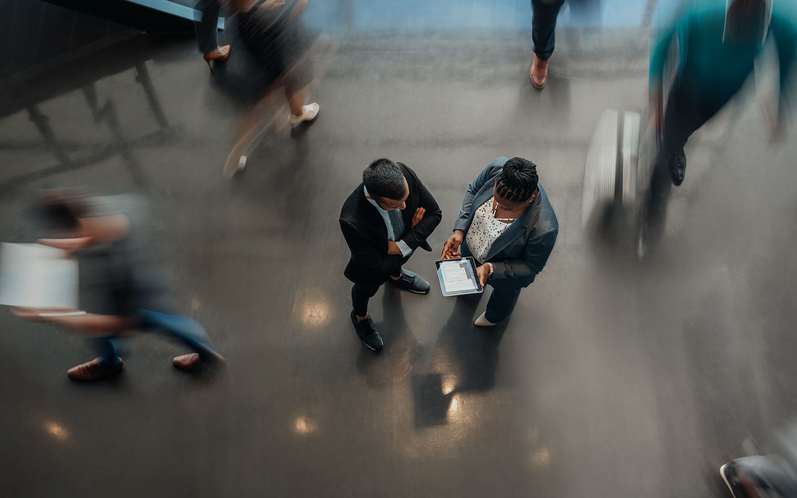 Two business people standing in the lobby of an office looking at a tablet