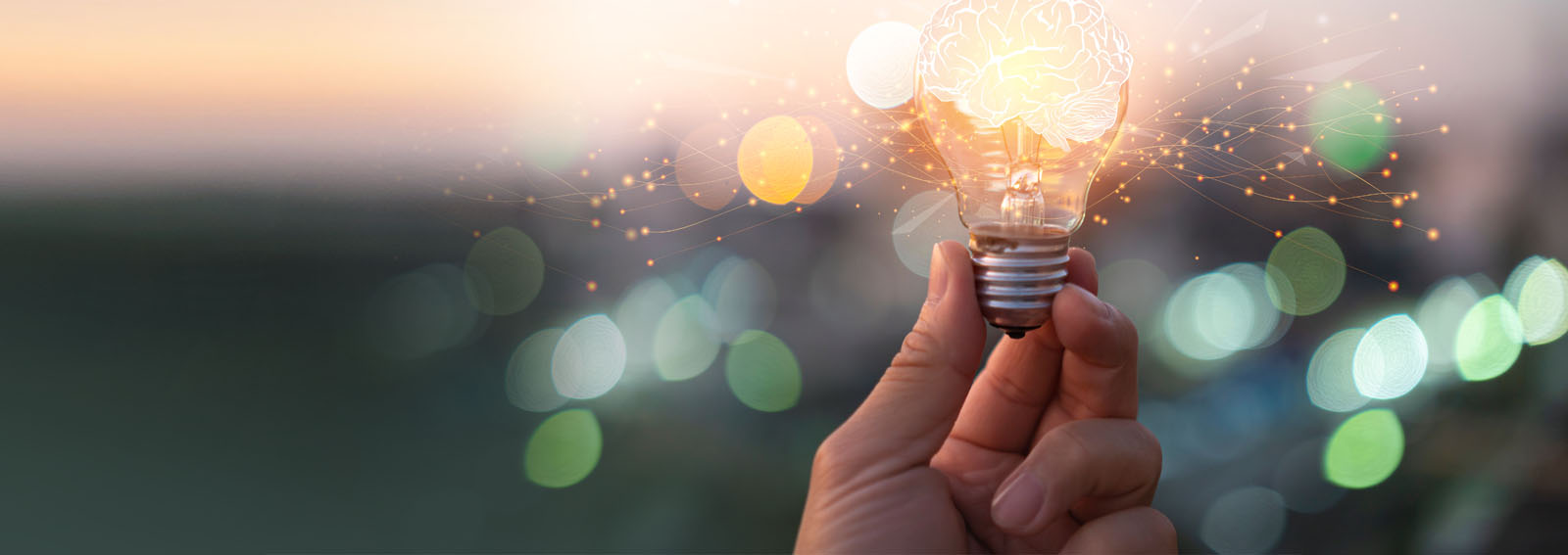 Person holding glowing lightbulb, blurred light in the background
