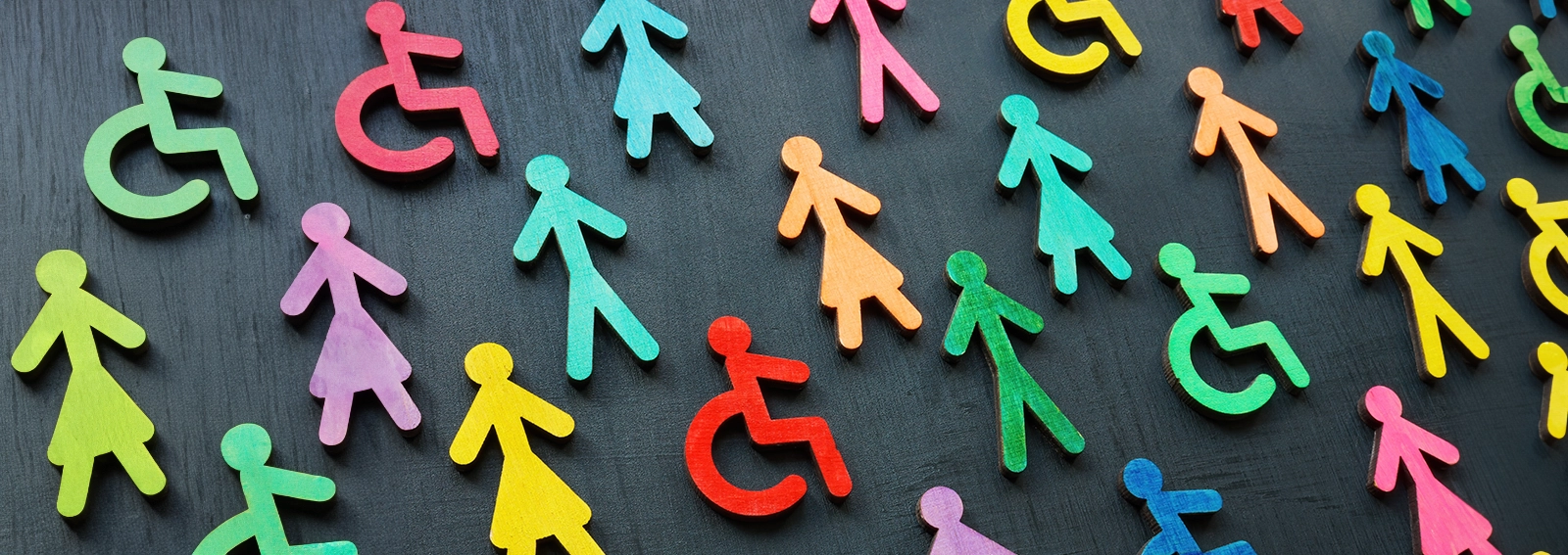 Colourful wooden shapes of people placed on a table.