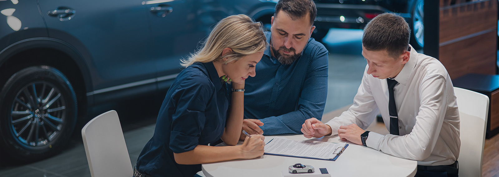Happy couple signs a contract for the purchase of a car dealership