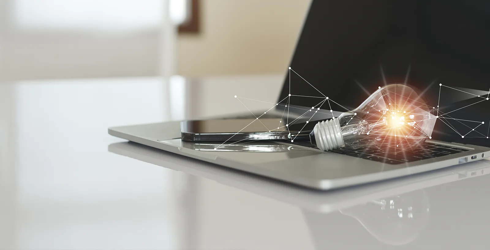 a light bulb sitting on a laptop to represent the electricity used to power the device