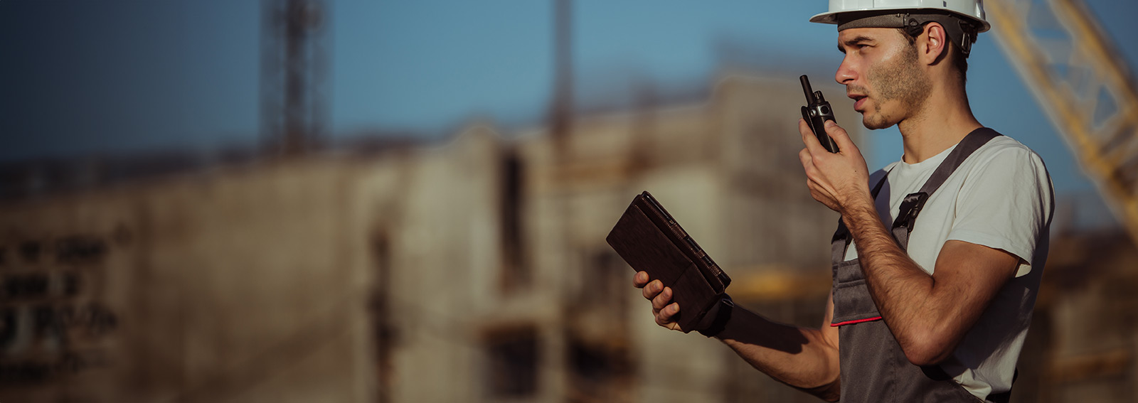 builder using a tablet and walkie talkie on a construction site