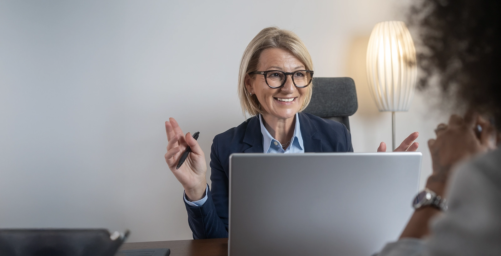 Credit union worker with her computer at desk talking to client