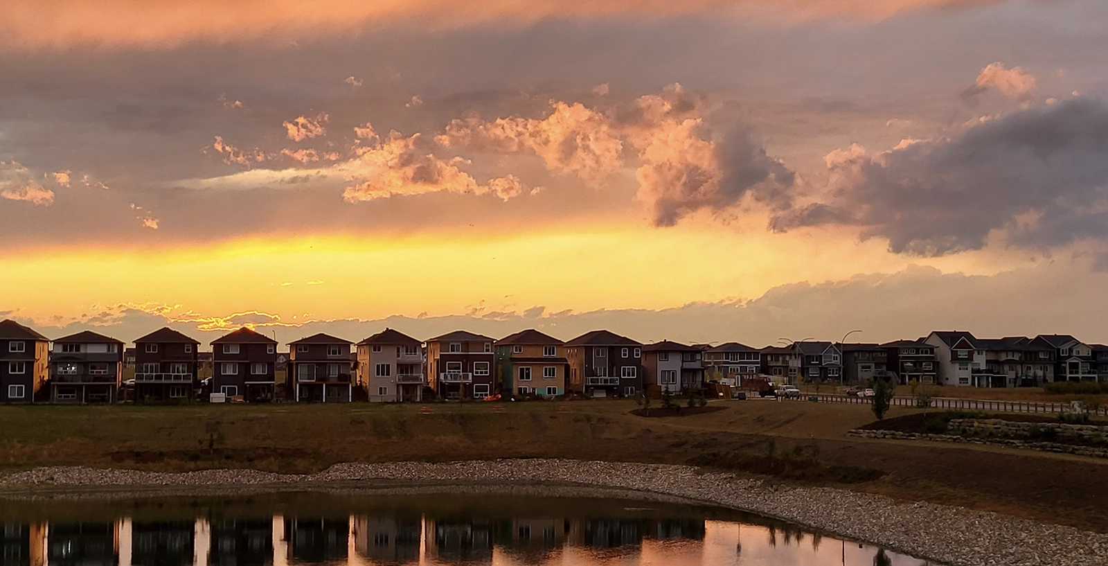 Row of houses with lake infront and a beautiful sunset sky