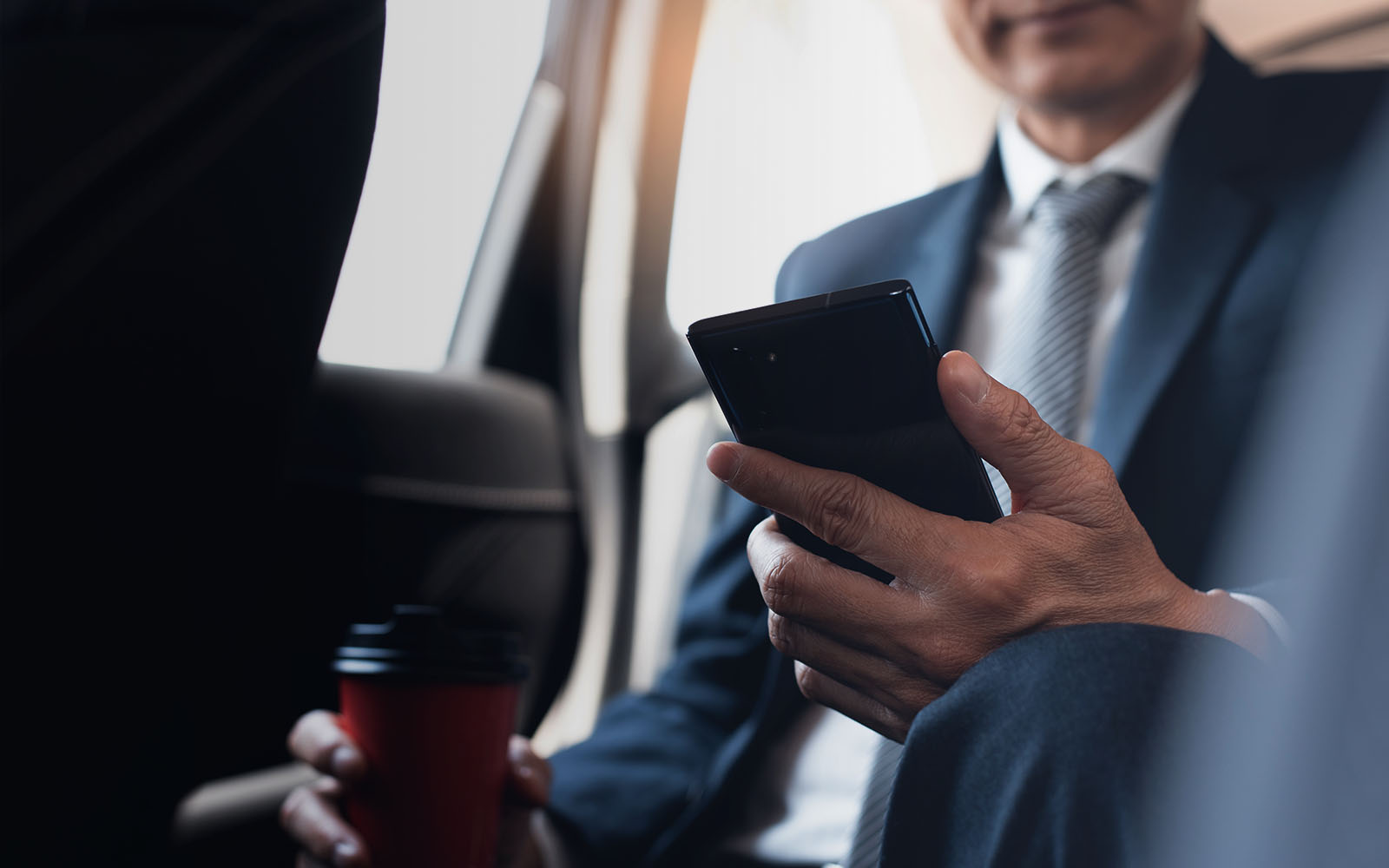 Businessman working on his phone while riding in a car jpg