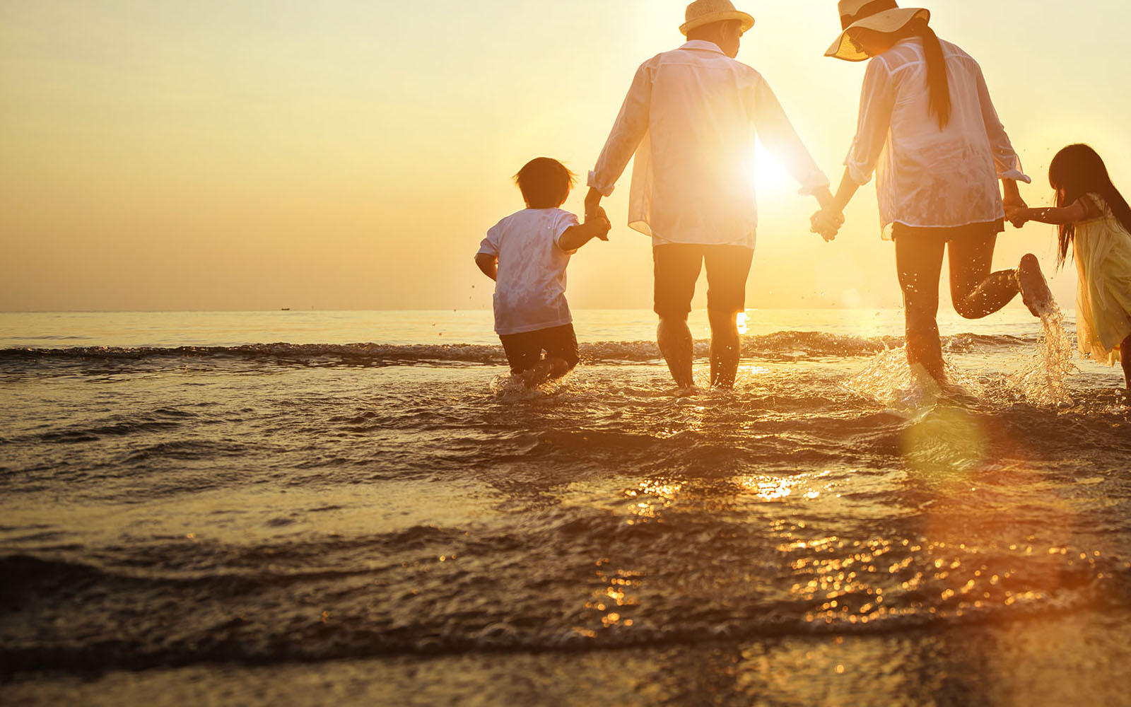 family running on the beach holding hands