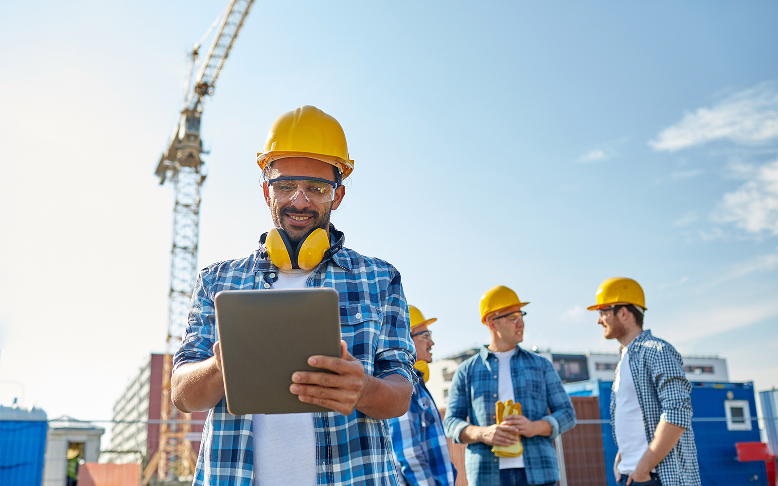 construction man standing in front of a crane with a clipboard