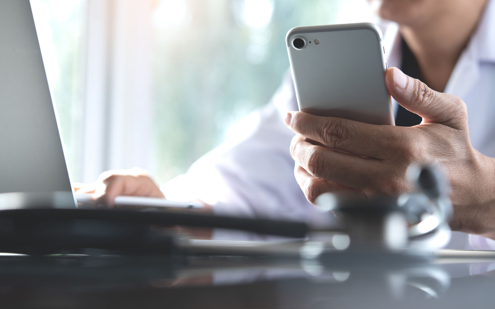 Person on cell phone while browsing on laptop