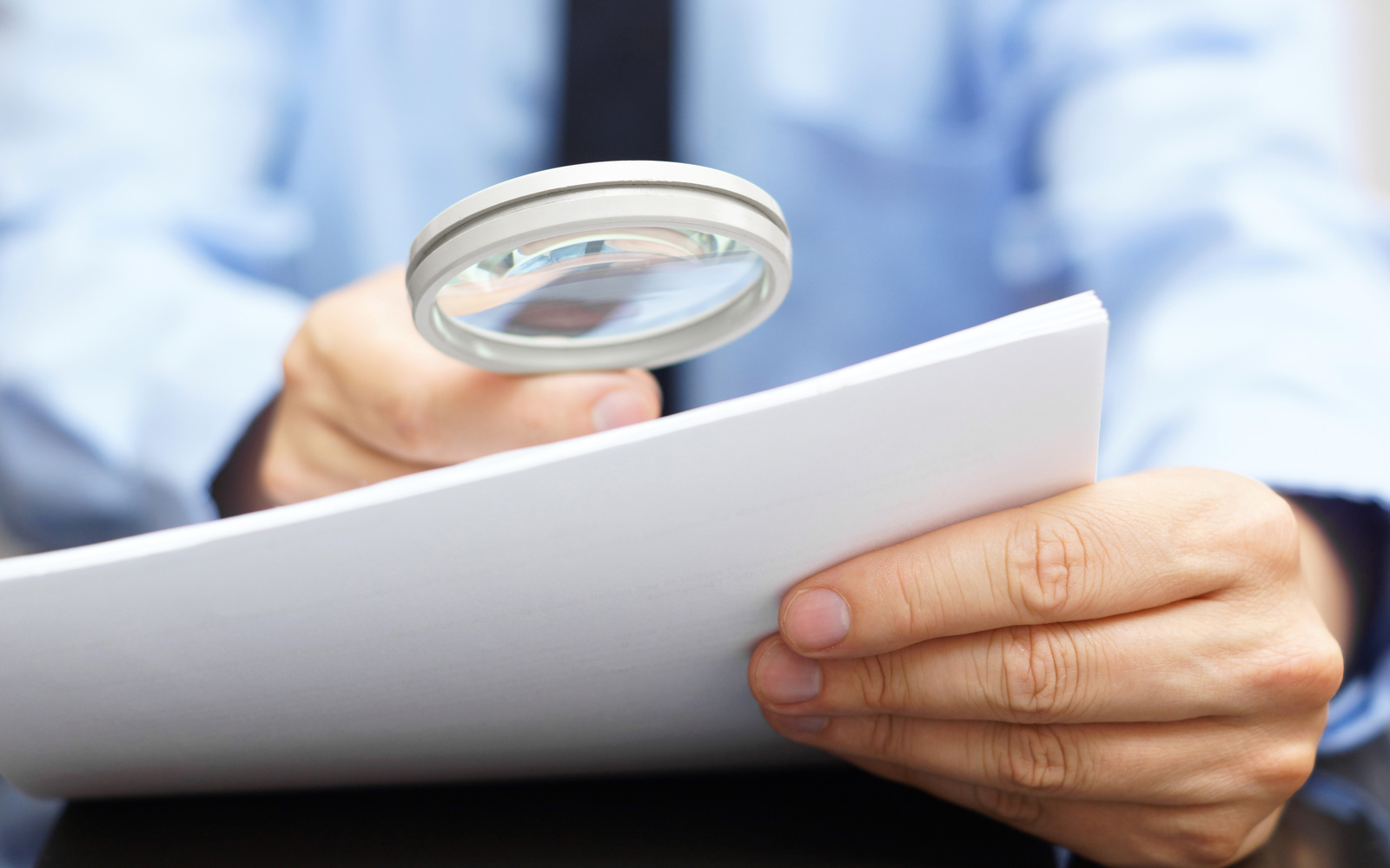 Businessman using magnified glass to read a document