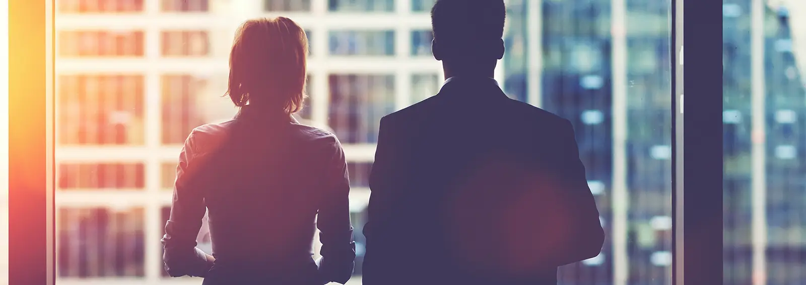 Two people staring out the window of an office building