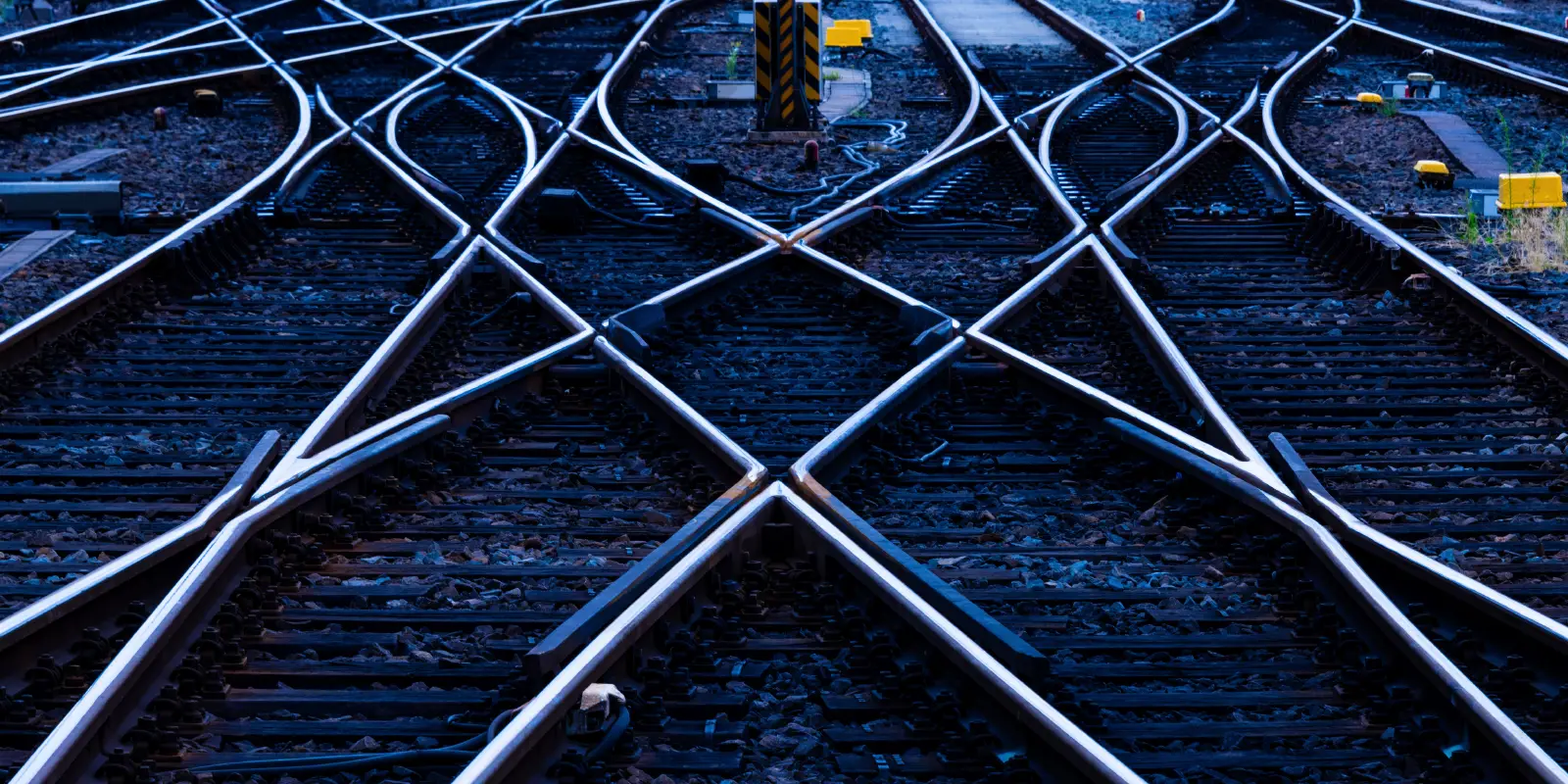Crisscrossing railway tracks with signal post.