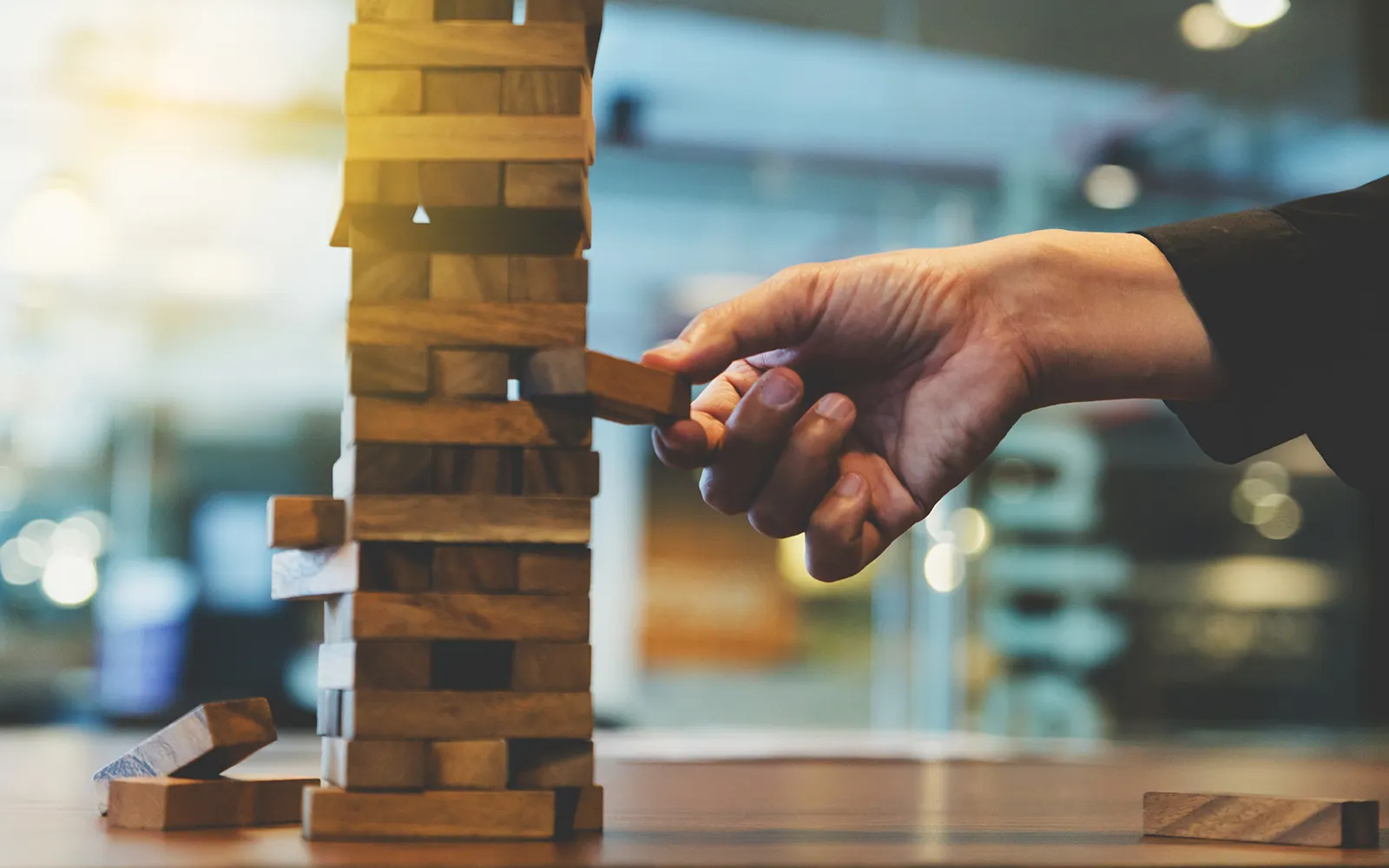 Close up of a Jenga tower and someone pulling out a piece