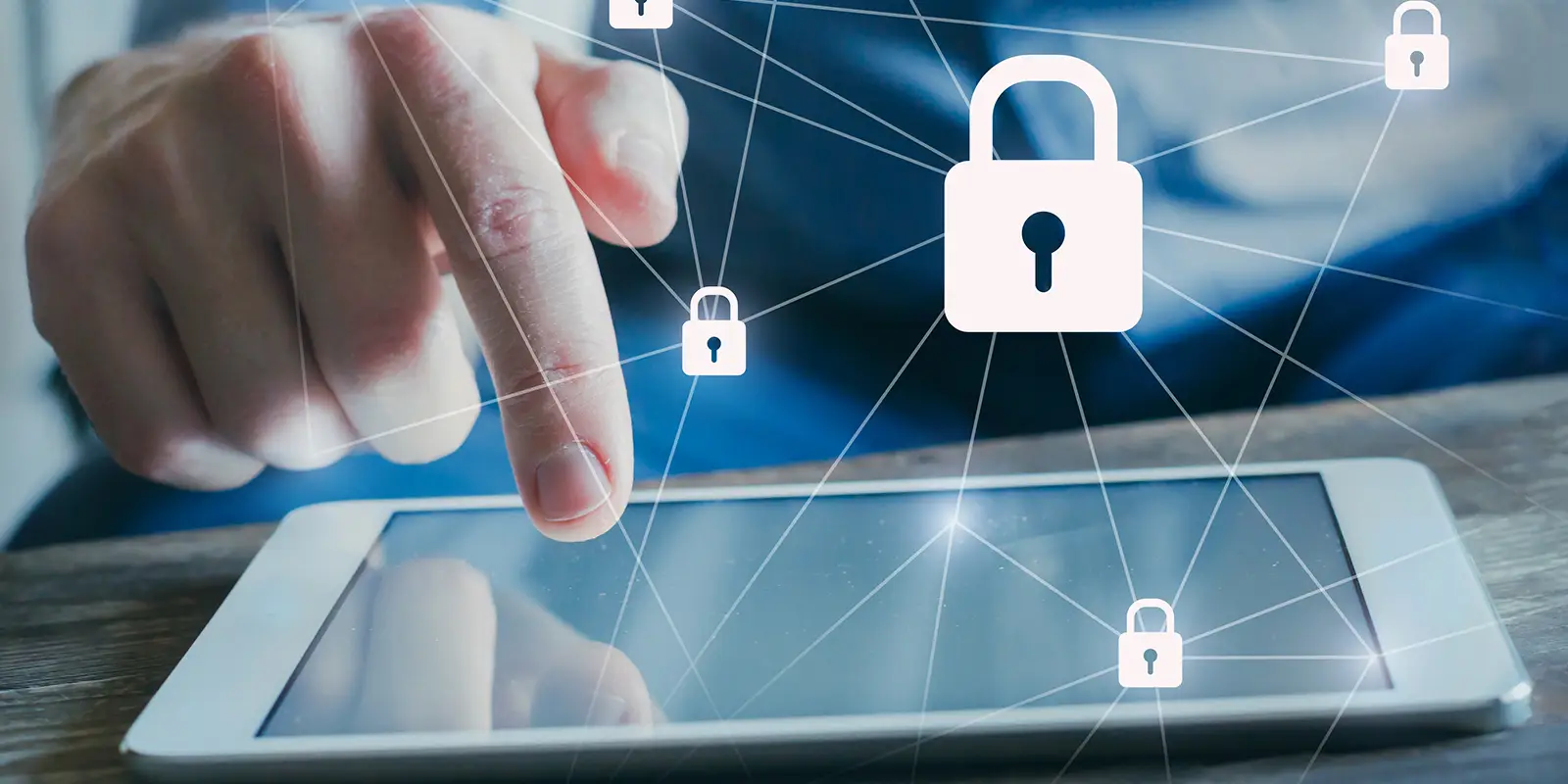 Close up of a hand using a tablet with icons symbolizing data protection and cybersecurity around it.