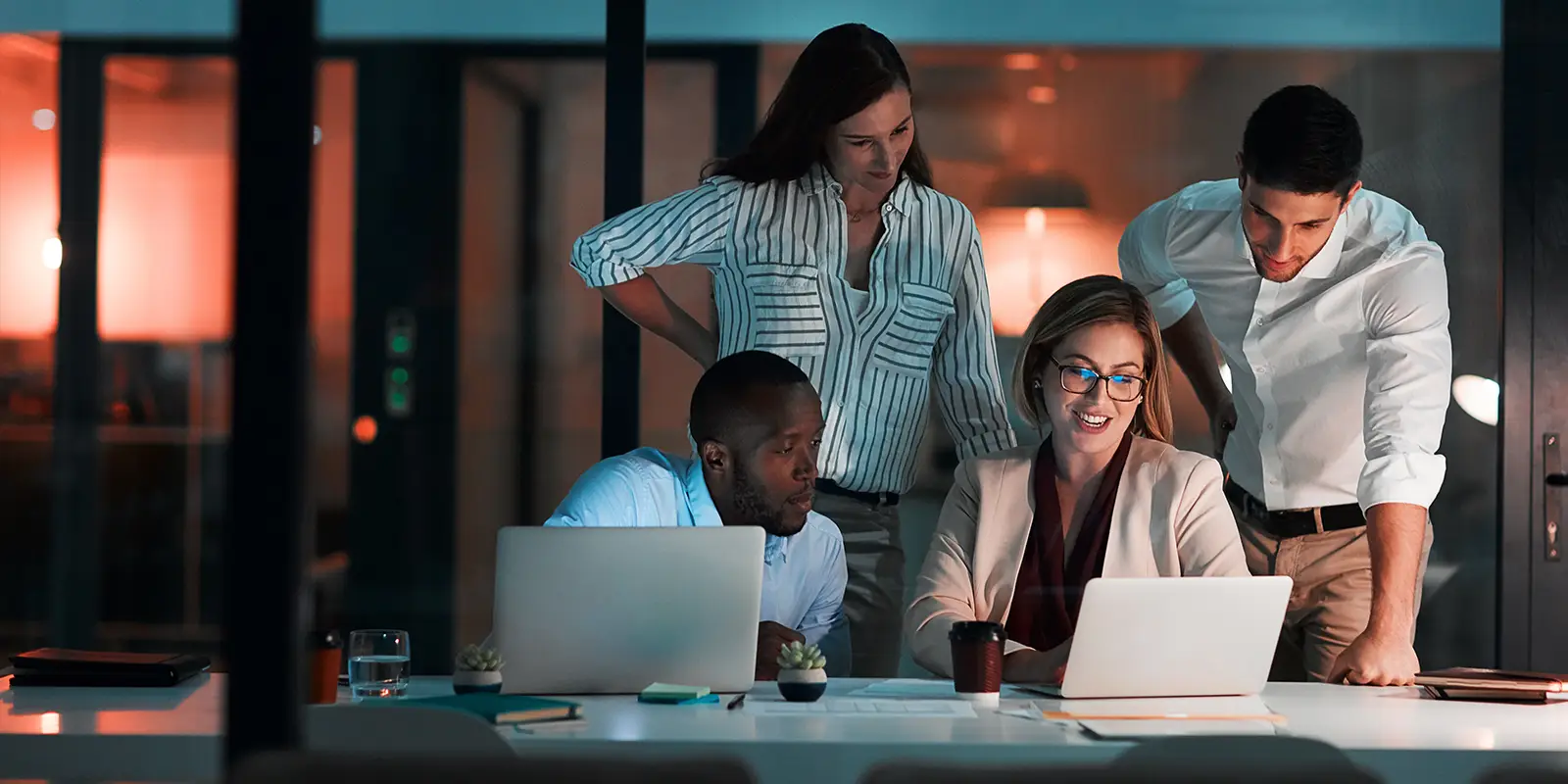Un groupe diversifié de professionnels collaborant sur des ordinateurs portables dans un environnement de bureau moderne.