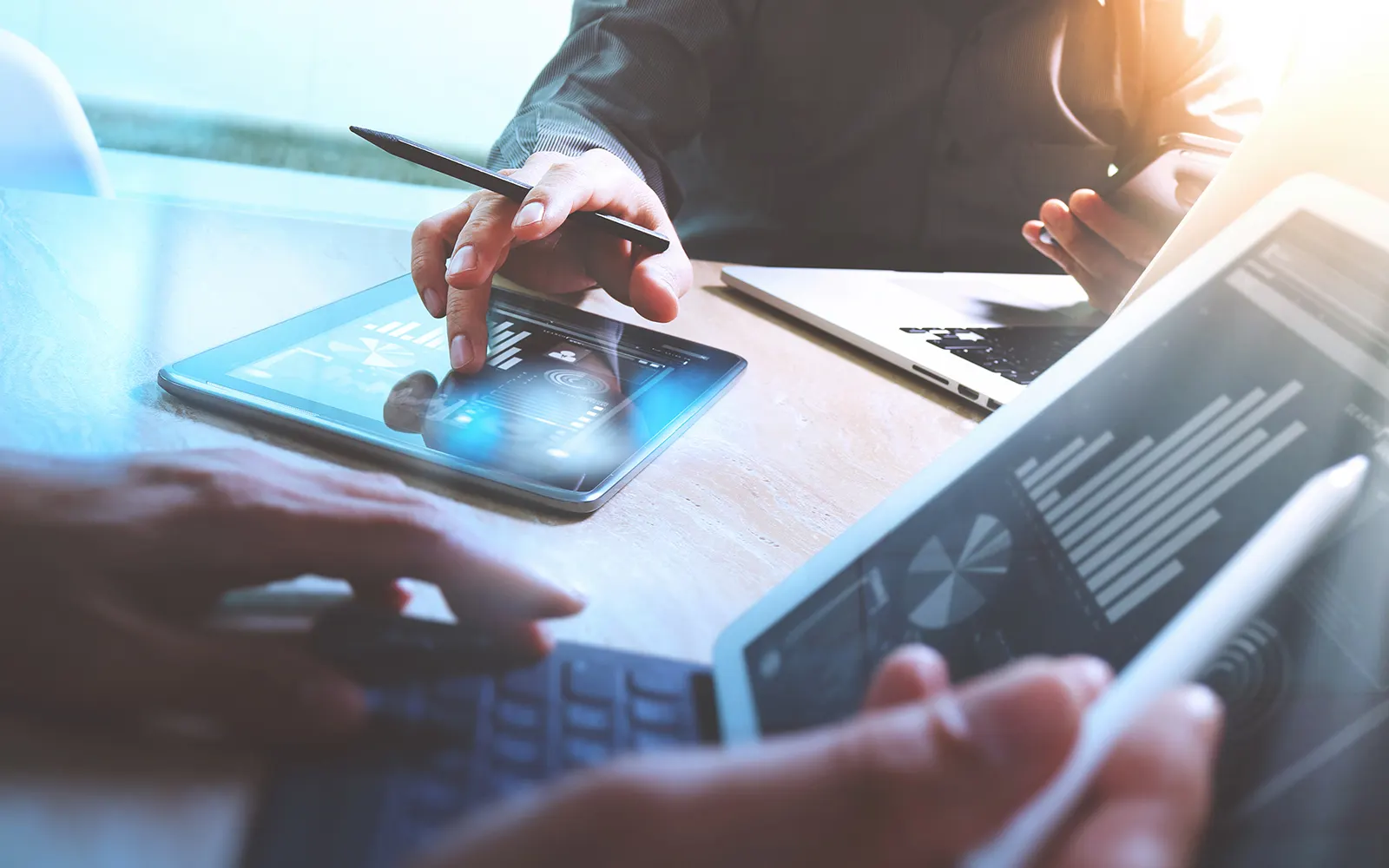 Close up of a person working on a laptop and another working on an iPad