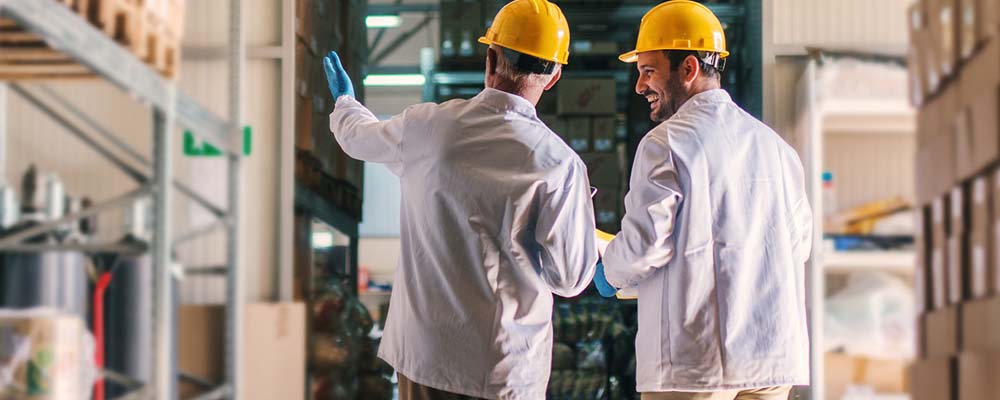 Two male workers in a warehouse smiling