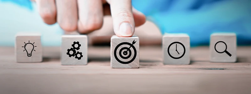 Finger pointing on a wooden block with a symbol on it representing targeted solutions.