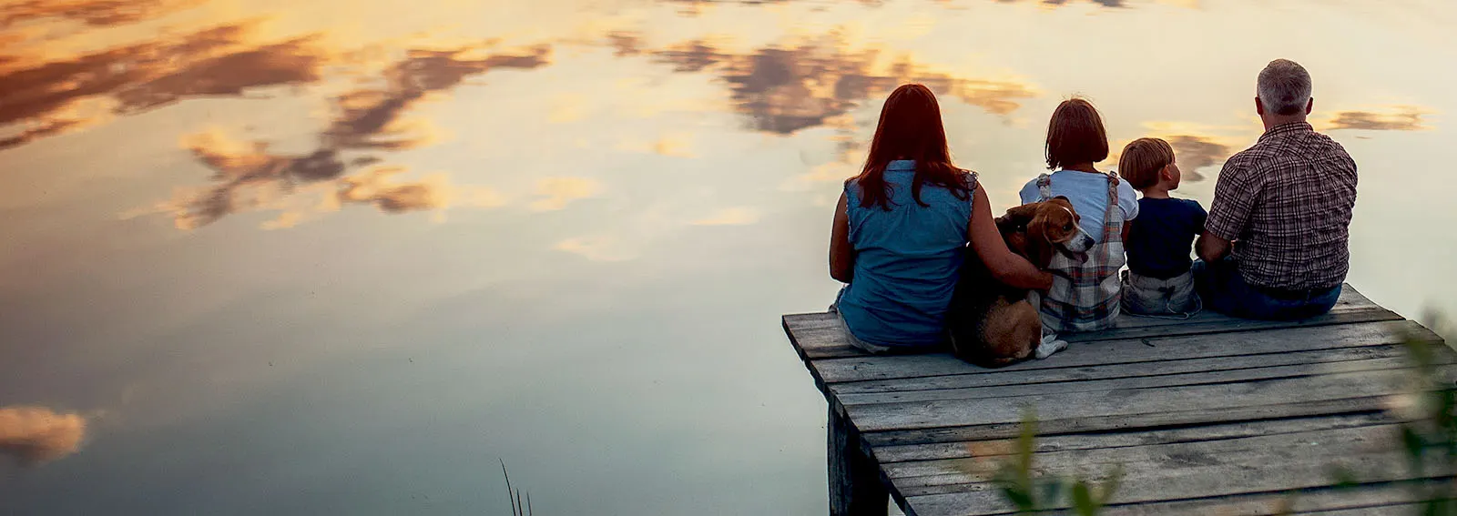 Family sitting on a dock during sunset