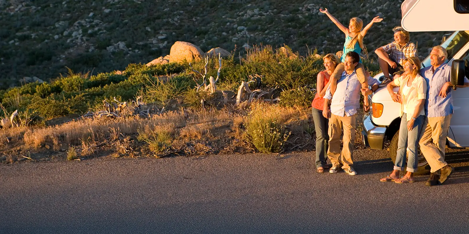 Multi-generation family relaxing in countryside on motor home vacation.
