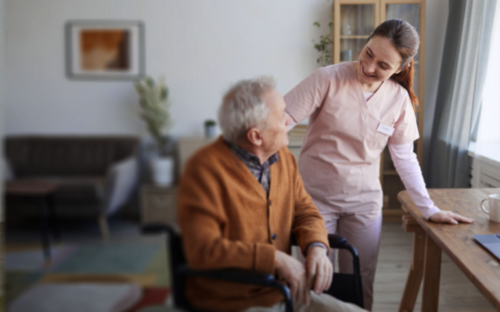 female nurse helping senior man in wheelchair at retirement home