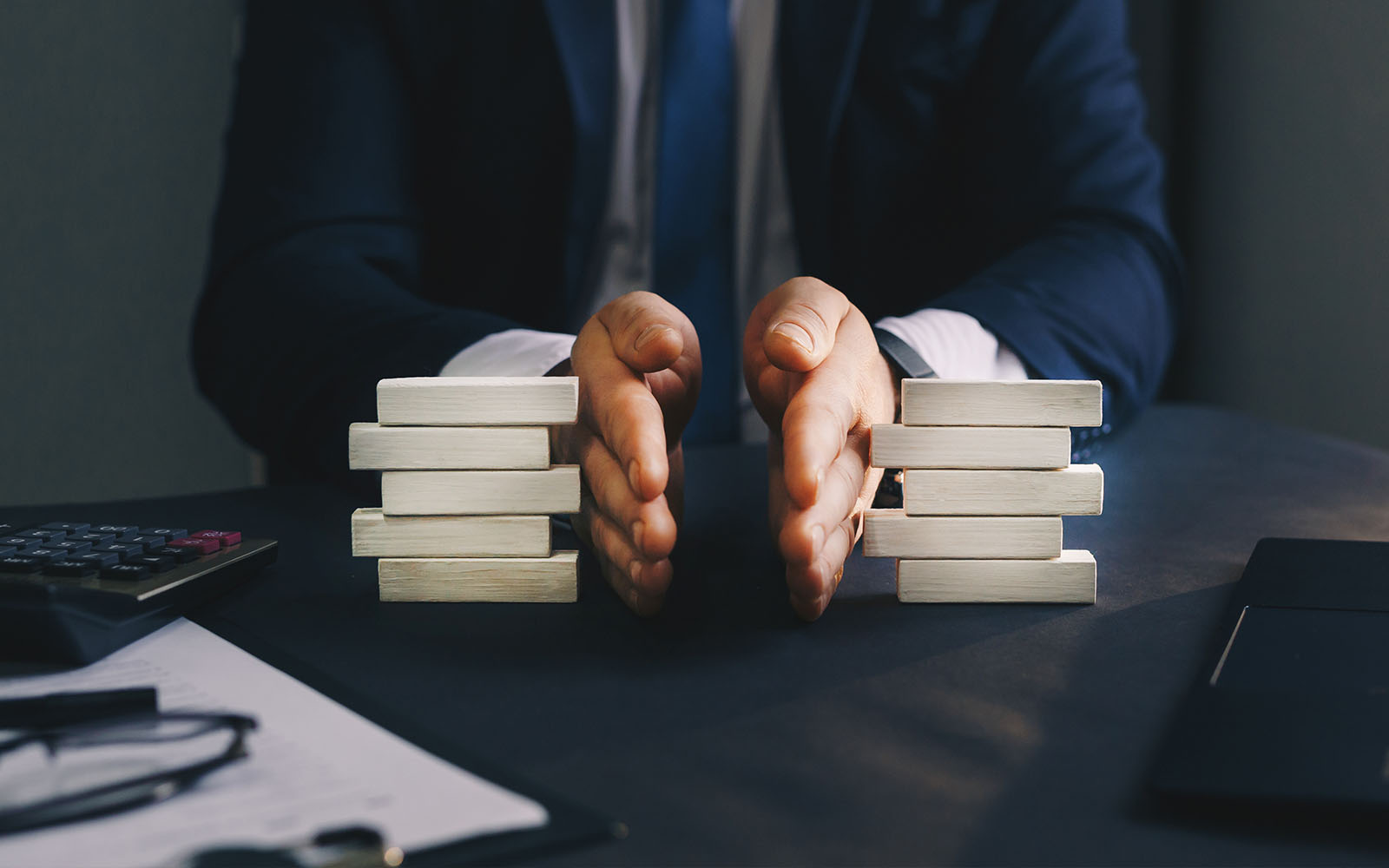 mans hands dividing wooden blocks on a desk