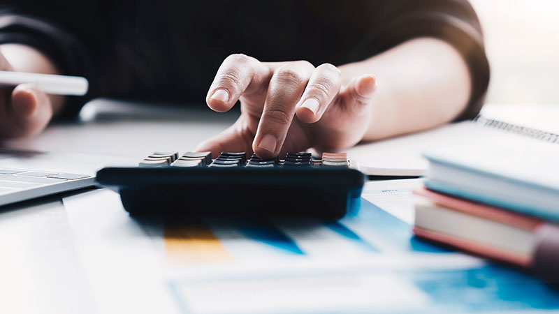 Hand typing on calculator at desk