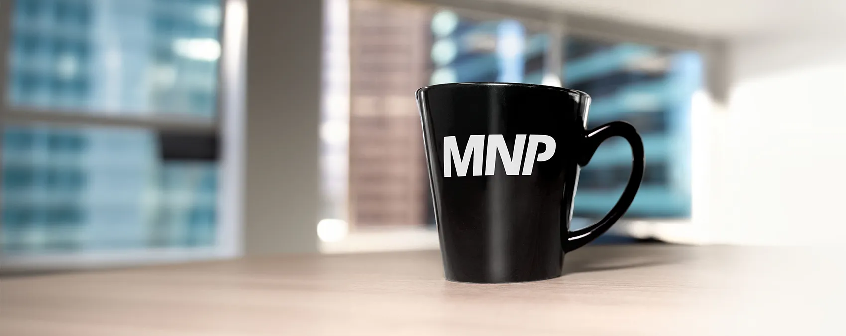 In a contemporary office setting, a mug featuring the MNP logo rests on a desk, embodying a sense of corporate elegance and professionalism.