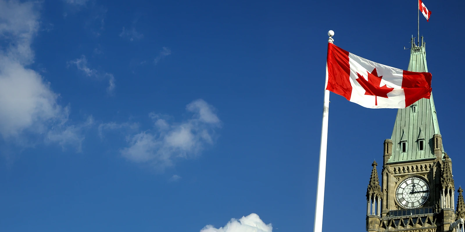 Canada flag with the Ottawa Parliament Building in the background.