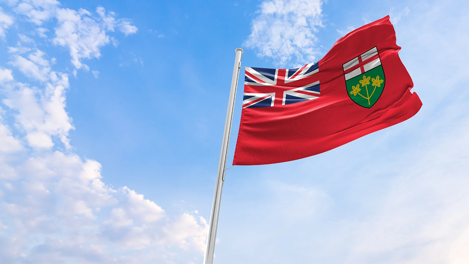 Ontario flag blowing in wind with sun and clouds in background
