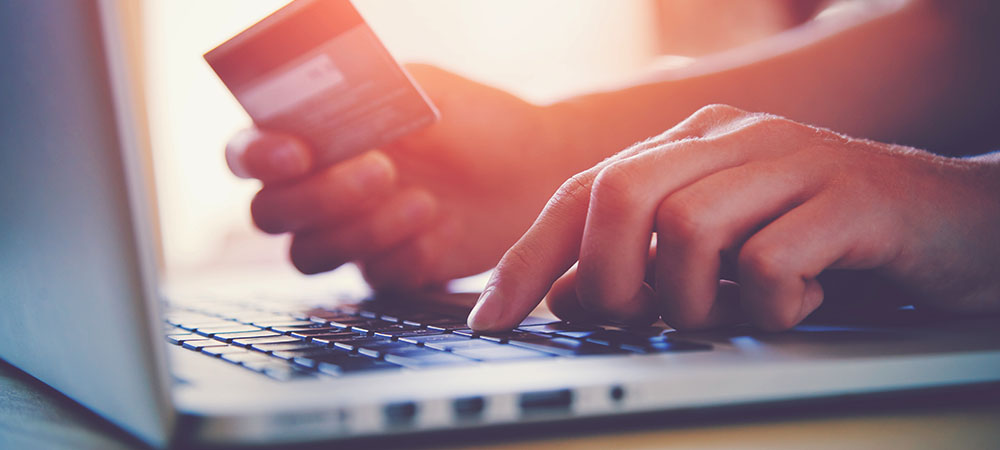 Hand typing in credit card numbers on laptop