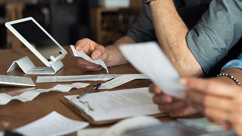 Personnes examinant des documents à table avec presse-papiers et tablette