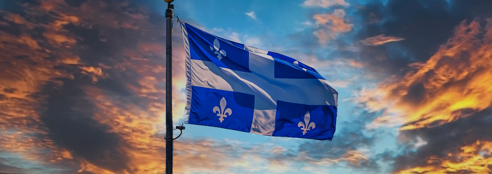 Quebec flag flying during a sunset