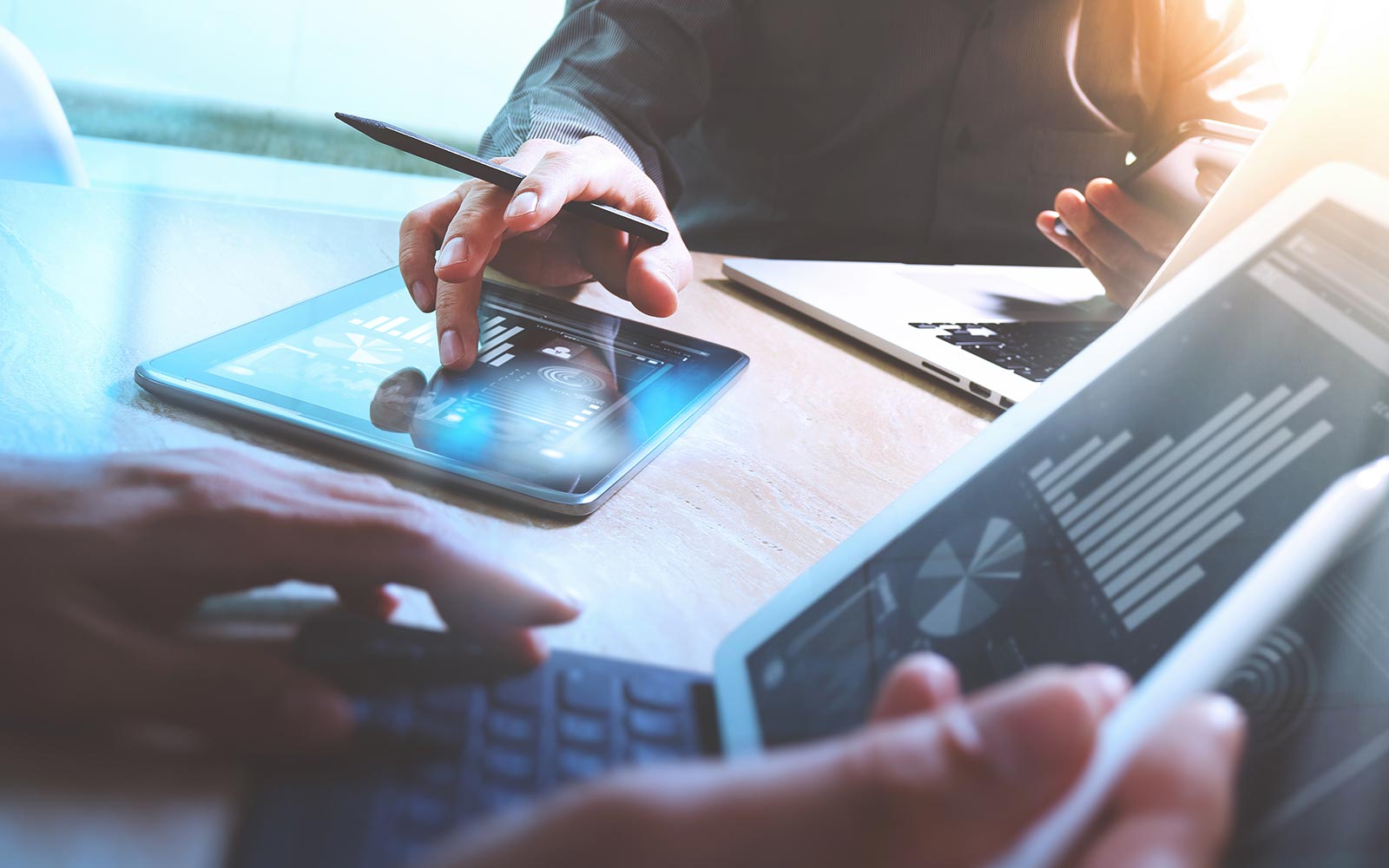 Close up of a person working on a laptop and another working on an iPad