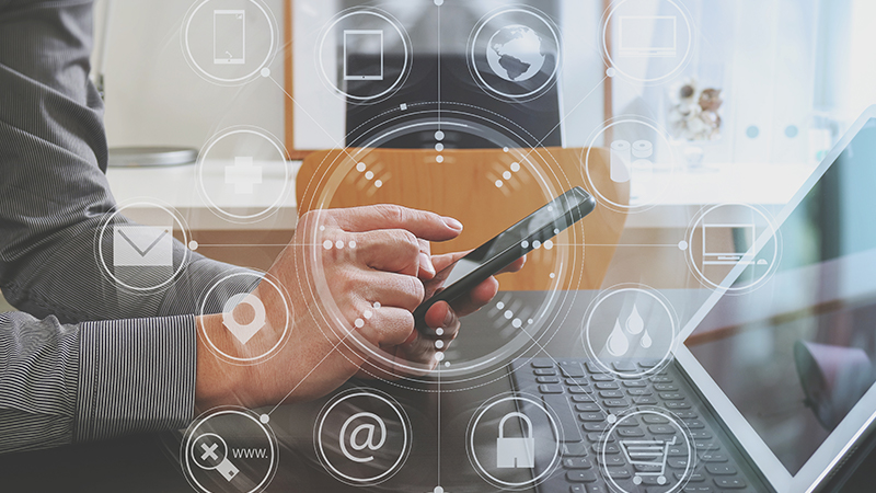 Digital composite image of businessman using cellphone with icons at desk